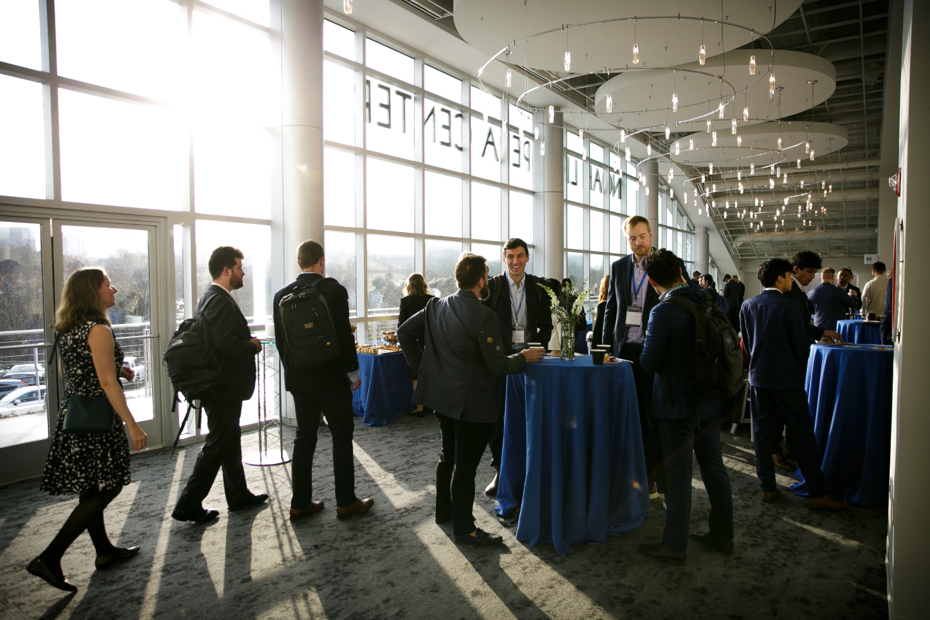 Attendees networking by floor-to-ceiling windows at the Noah Liff Opera Center