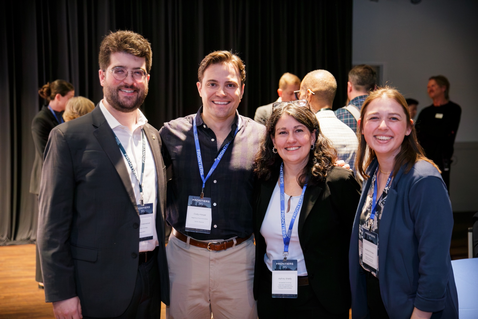 Four attendees with Frontiers badges smiling together
